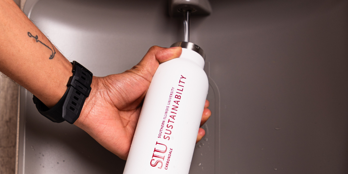 Student uses water refill station with a SIU Sustainability water bottle