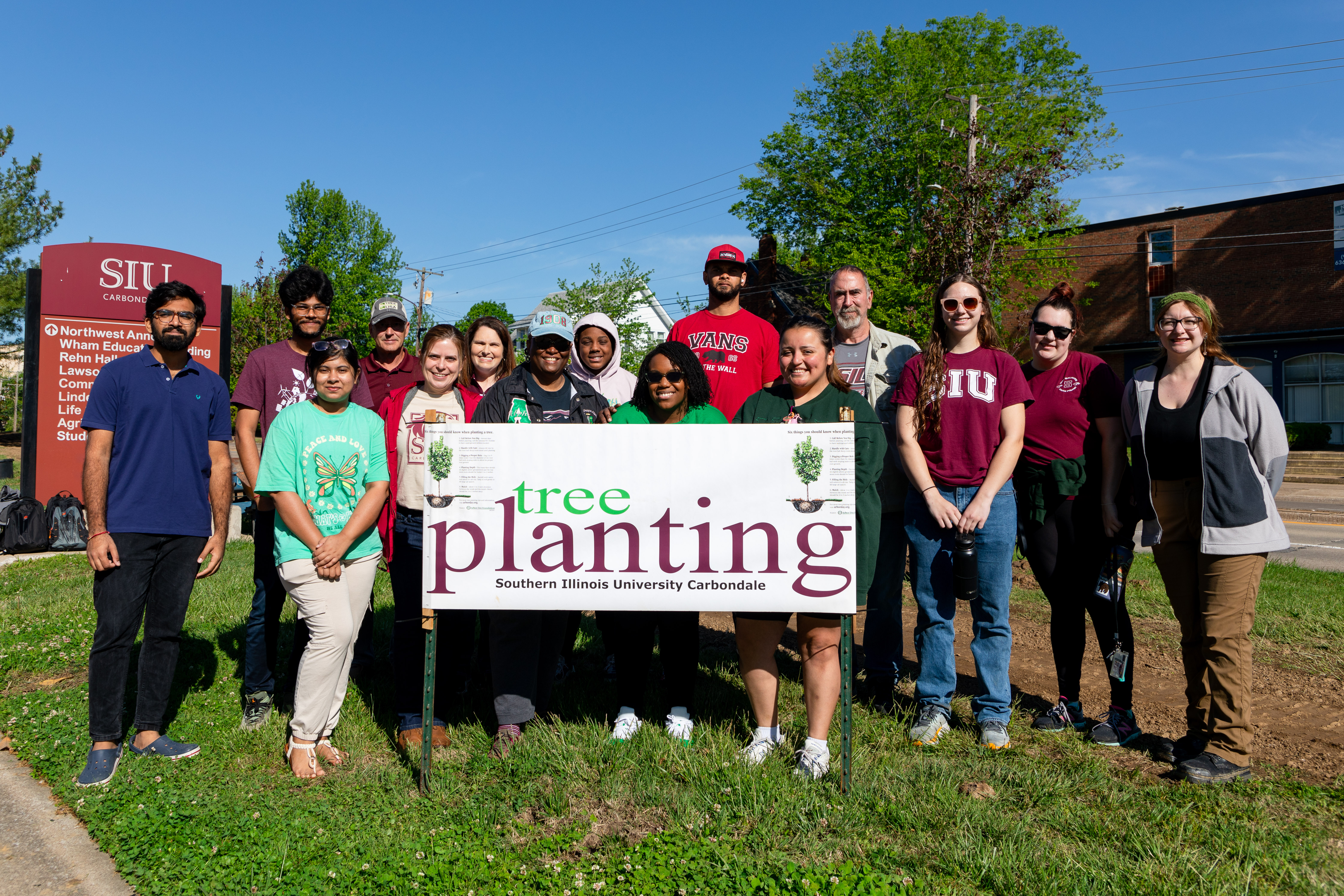 Spring 2024 Tree planting group behind the tree planting sign